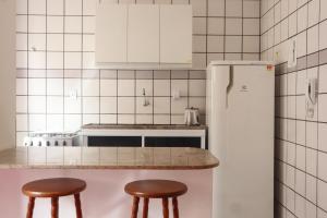 a kitchen with two stools and a white refrigerator at Apartamento a 350 metros da Praia do Morro in Guarapari