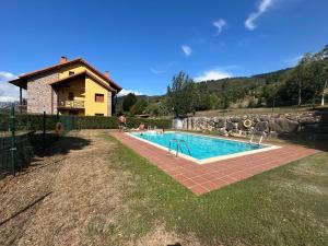 a swimming pool in a yard next to a house at El refugio de Liébana in Ojedo