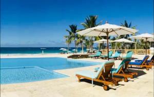 - une piscine avec des chaises et des parasols ainsi qu'une plage dans l'établissement Cana Rock Star D209 Jaccuzi Pool Golf and Private Beach, à Punta Cana