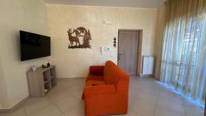 a living room with an orange couch and a tv at Il Rifugio dell'Orso in Castel di Sangro