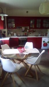 una cocina con mesa, sillas blancas, mesa y sillón en Casa nel Bosco, en Pino Torinese