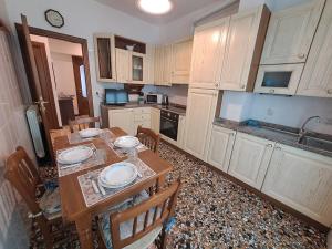a kitchen with a wooden table with chairs and a tableasteryasteryasteryasteryastery at Appartamento Miramare in Vado Ligure +29 photos