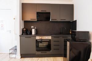 a kitchen with gray cabinets and a microwave at Le Soleil Cormeillais in Cormeilles-en-Parisis
