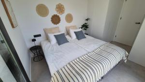 a bedroom with a large bed with white sheets and blue pillows at Casa Soluna -Santa Rosalia Lake and Life Resort in Torre-Pacheco +32 photos