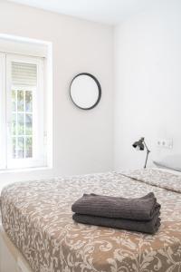 a white bedroom with a bed with a round mirror on it at Tu casa en Madrid in Madrid