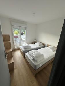 two beds in a room with a window at Appartement climatisé in Château-Arnoux-Saint-Auban