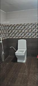a white toilet in a bathroom with a tile wall at Raja Home stay in Tiruvannāmalai