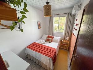 a small bedroom with a bed with a window at Pousada Surf na Guarda in Guarda do Embaú