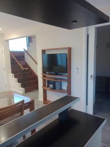 a living room with a television and a staircase at Bosque de Ciruelos in Carilo