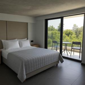 a bedroom with a bed and a balcony with a table at Hesperian Luxury Villas in Chania Town