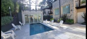 a patio with white chairs and a swimming pool at Bosque de Ciruelos in Carilo