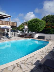a swimming pool with blue water in front of a house at Ti Village Creole in Sainte-Anne