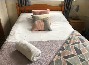 a bed with three pillows and a blanket on it at 284 - Room 3 - Beachfront in Swansea +1 photo