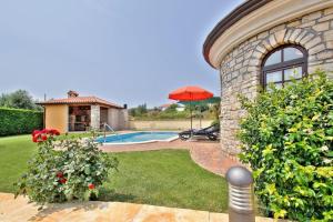 a stone house with a swimming pool and an umbrella at Villa Morena by Briskva in Kaštel