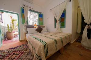 Un dormitorio con una cama y una ventana grande. en Dar Soufian, en Ouarzazate
