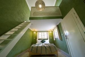 Habitación verde con cama y escalera en Dar Soufian, en Ouarzazate