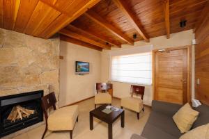 a living room with a fireplace and a stone wall at Del Sauco Apart & Spa in San Martín de los Andes