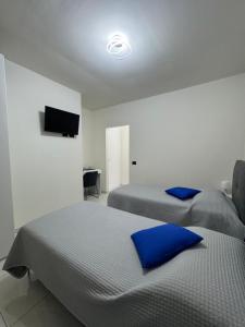 two beds with blue pillows in a bedroom at B&B Orio Affittacamere Foresteria Lombarda in Grassobbio