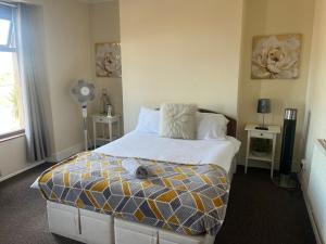 a bedroom with a bed and two tables and a fan at 284 - Room 5 - Beachfront - Fantastic sea views in Swansea