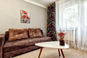 a living room with a brown couch and a table at Arbat апартаменты в центре города - выбор для туриста и деловых поездок in Almaty +12 photos