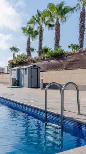 a swimming pool with palm trees in the background at Albergue Las Salinas in San Pedro del Pinatar