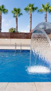 a fountain in the middle of a pool with palm trees at Albergue Las Salinas in San Pedro del Pinatar