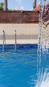 a swimming pool with a water fall in front of it at Albergue Las Salinas in San Pedro del Pinatar