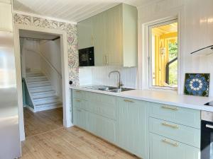 a kitchen with white cabinets and a sink and a staircase at The Nordby Cabin - Bed Linen Included - 3 minutes from E6 in Strömstad