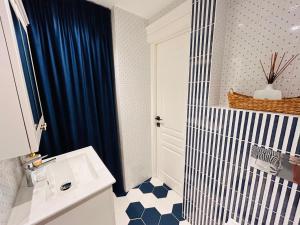 a bathroom with a blue shower curtain and a sink at Apartamentai senamiestyje Klaipėdos inkarai in Klaipėda +24 photos