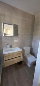 Un baño con lavabo, inodoro y espejo. en El rincon, en Cambados