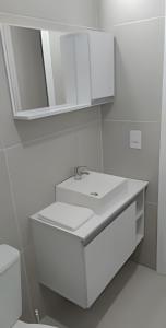 a white bathroom with a sink and a mirror at Apartamento POP Panazzolo in Caxias do Sul