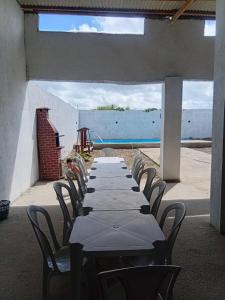 einen langen Tisch mit Stühlen und das Meer im Hintergrund in der Unterkunft Recepções3d casa aconchegante com piscina in Campina Grande