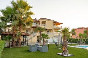a large building with palm trees and a pool at Villa Ilianna in Igoumenitsa