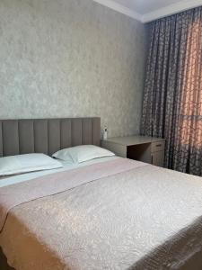 a bedroom with a bed and a desk and a window at Посуточно 3 комн в ЖК Аль Фараби in Shymkent