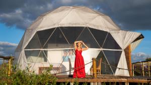 a woman in a red dress standing in a tent at Glamping Hidden Treasure in Alto Paraíso de Goiás