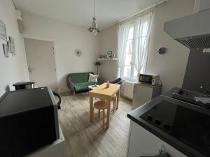 a kitchen and living room with a table and a couch at Le Papillon bleu in Asnelles