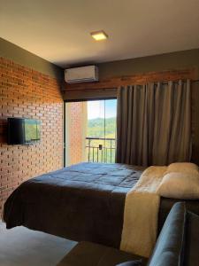 a bedroom with a bed and a window with a tv at Villa da Serra Studios Ibitipoca in Conceição da Ibitipoca
