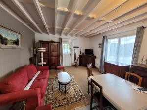 a living room with a red couch and a table at Gîte le cyprès in Tigy