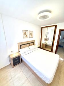 a bedroom with a large white bed and a mirror at Pretty Bungalow Apartments in Polop