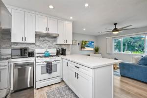 a kitchen with white cabinets and a blue couch at Seabreeze 1BR, Walk to Sand, Pet Friendly, Parking, Fire Pit Access in Carlsbad