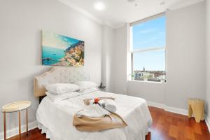 a bedroom with a white bed with a large window at XL Studio - Studio with Pool & Scenic Rooftop in Philadelphia +29 photos