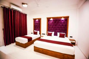 two beds in a hotel room with red curtains at Kudila Resort in Anuradhapura