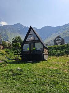a small house in a field with mountains in the background at Rocky Views in Kazbegi