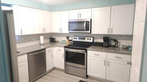 a kitchen with white cabinets and a stove and microwave at Blue Horizon Lake House - Renovated 3BR 2BA on the Beach in Bay City