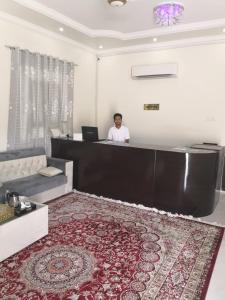 a man sitting at a reception desk in a room at Ras Al Jinz Turtle Guest House in Junayz al Janūbī