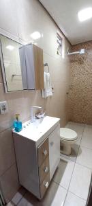 a bathroom with a sink and a toilet and a mirror at Apartamento térreo climatizado próximo a praia in Itapema +32 photos