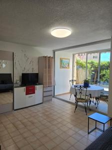 a living room with a table and a kitchen with a dining room at 2 pièces en rez- de -jardin in Saint-Raphaël