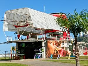 een gebouw met een reclamebord en een palmboom bij Cobertura com churrasqueira São Vicente in São Vicente