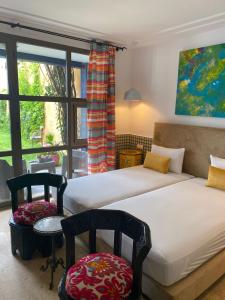 a bedroom with two beds and two chairs and a window at Riad Maison de ville piscine privée in El Jadida +73 photos