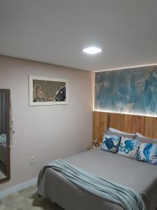 a bedroom with a bed and a painting on the wall at Apartamento térreo climatizado próximo a praia in Itapema